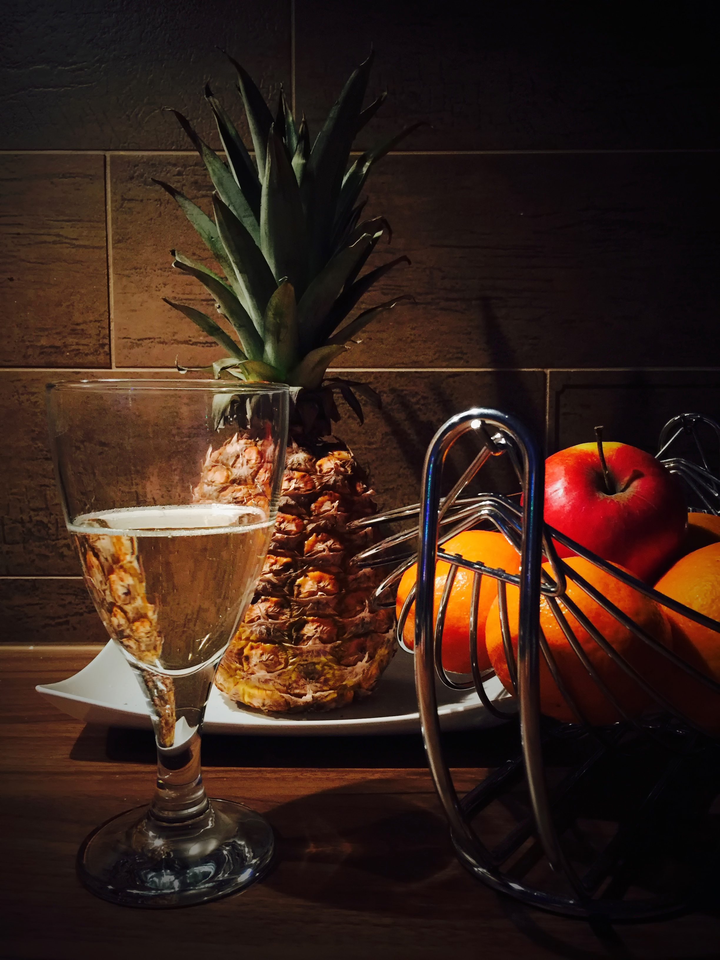 ananas s mísou ovoce a skleničkou bílého vína 
